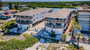 A two-story building with a balcony, outdoor seating, and a view of a marina.
