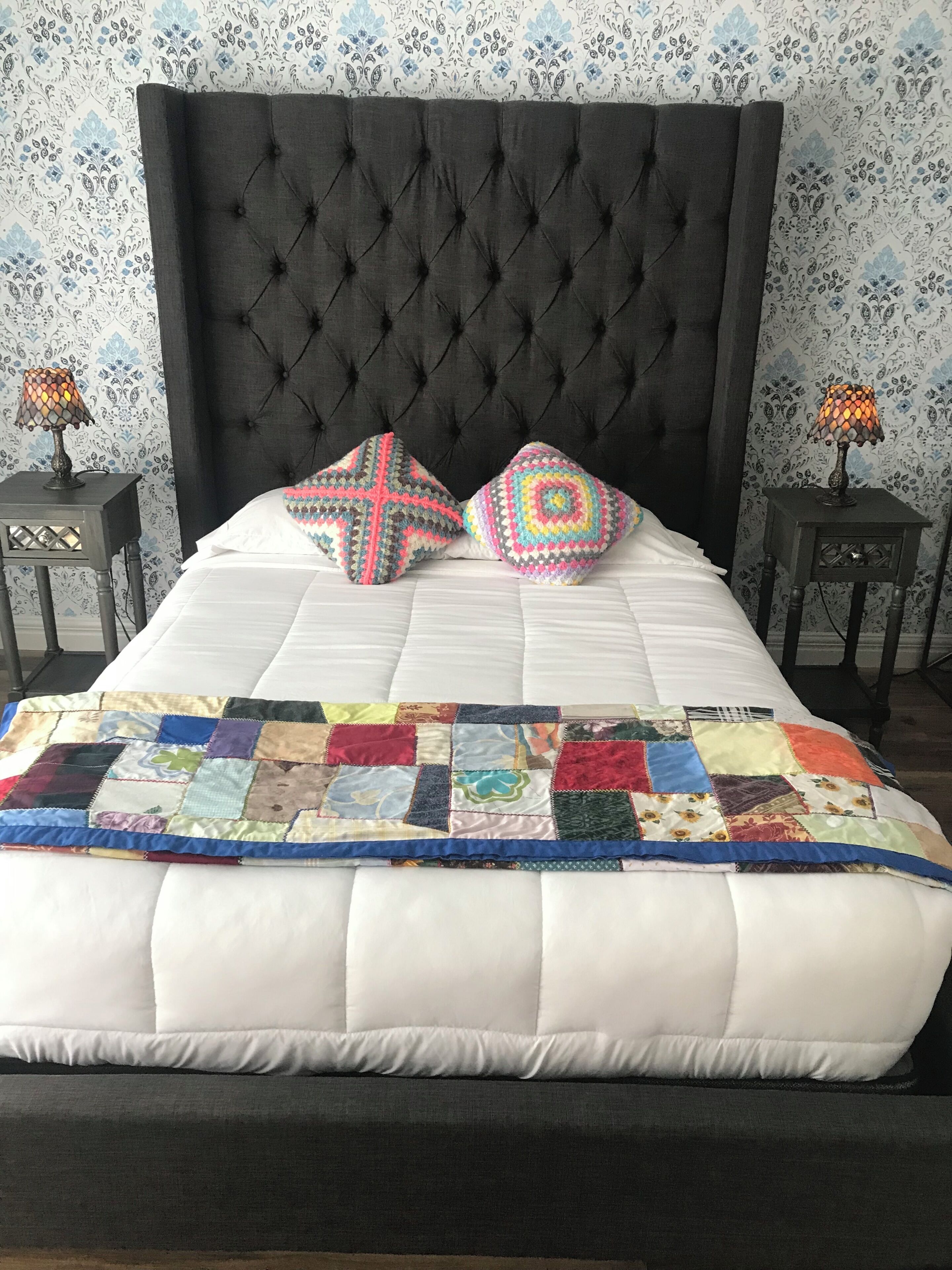 Una cama con colcha, dos almohadas y dos lámparas de noche.