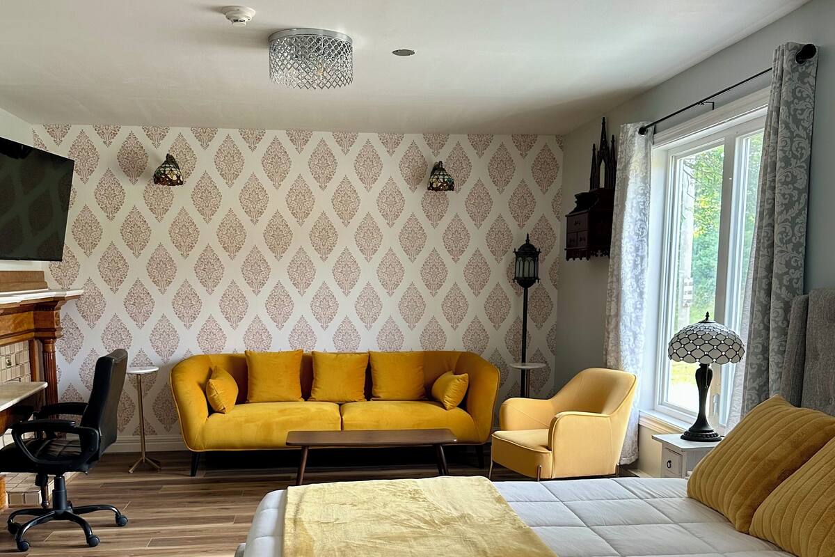 Una habitación con cama, sofá, sillón, una mesita y un escritorio.