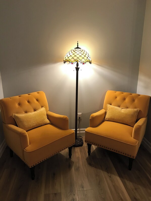 Two armchairs with matching cushions, a floor lamp with a patterned shade, and a wooden floor.