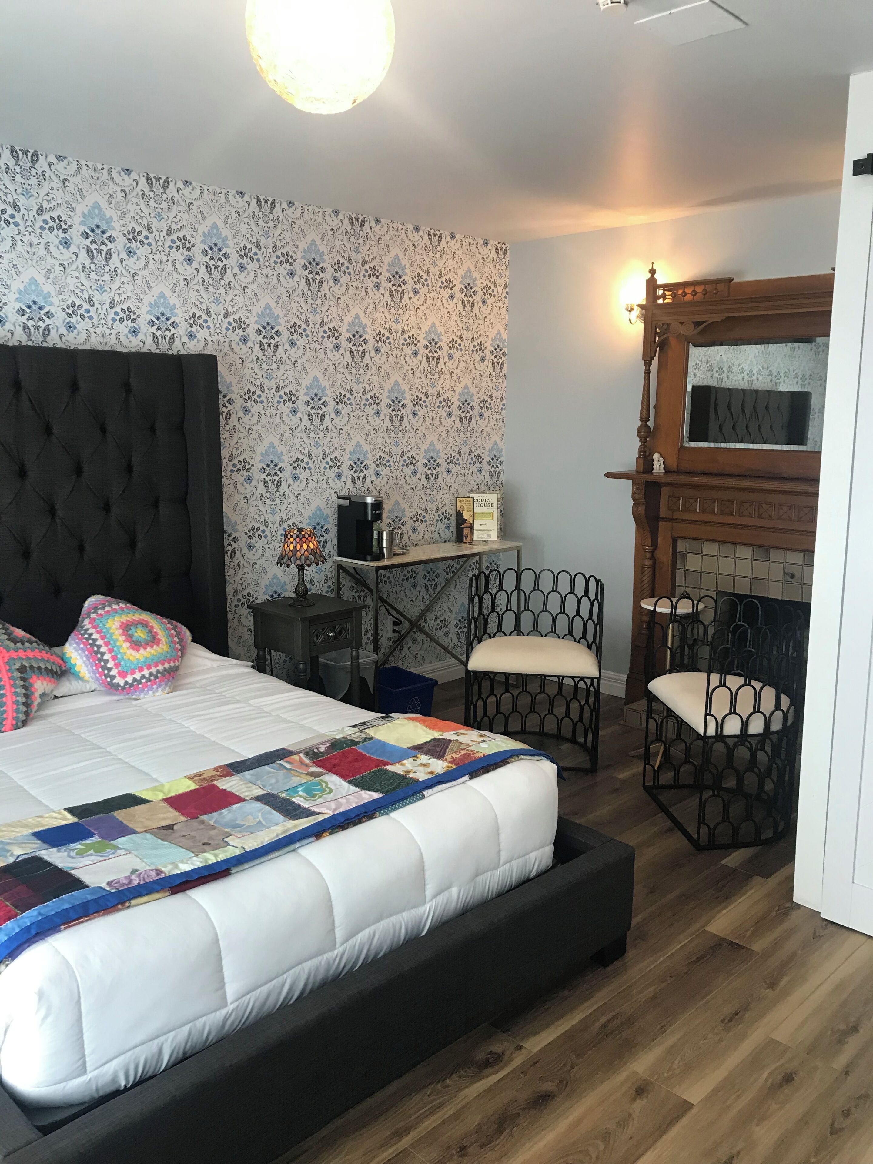 Een slaapkamer met een groot bed, een koffiezetapparaat, een bureau en een open haard.
