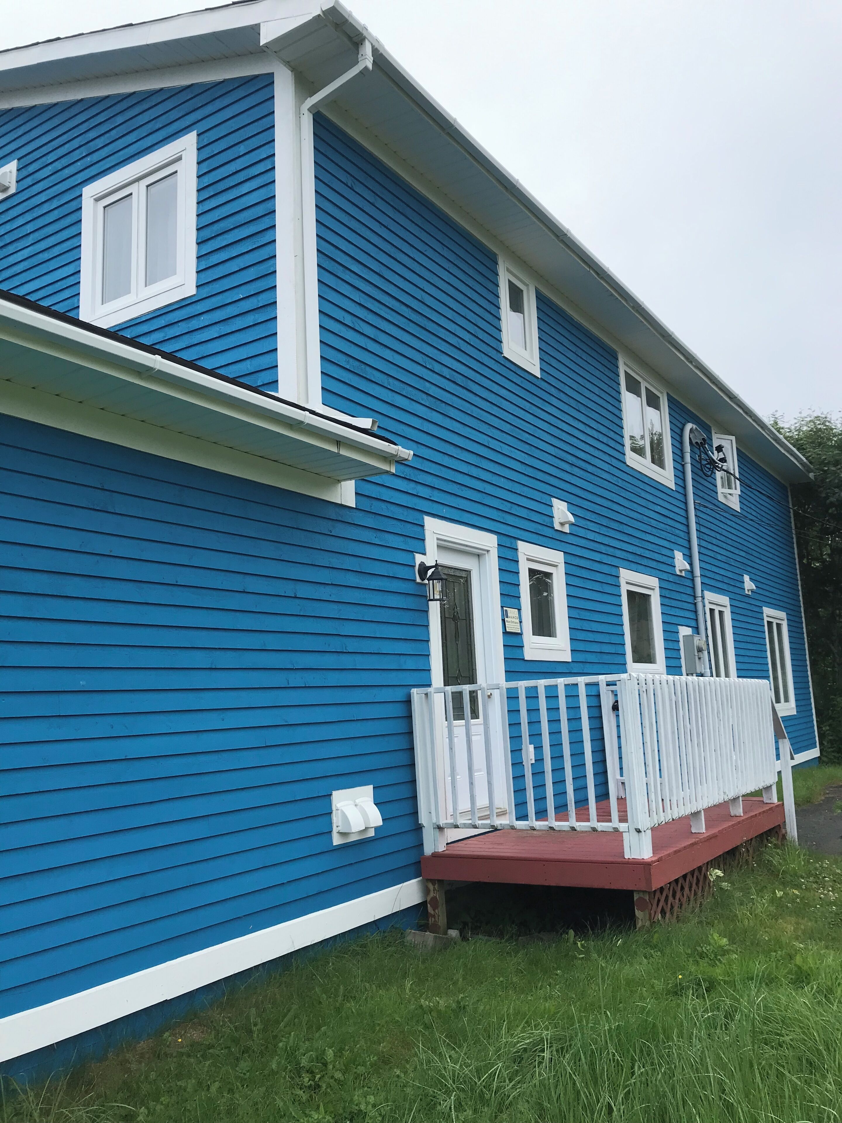 A blue house with a white porch and a red roof.