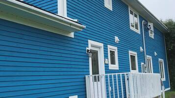 A blue house with a white porch and a red roof.