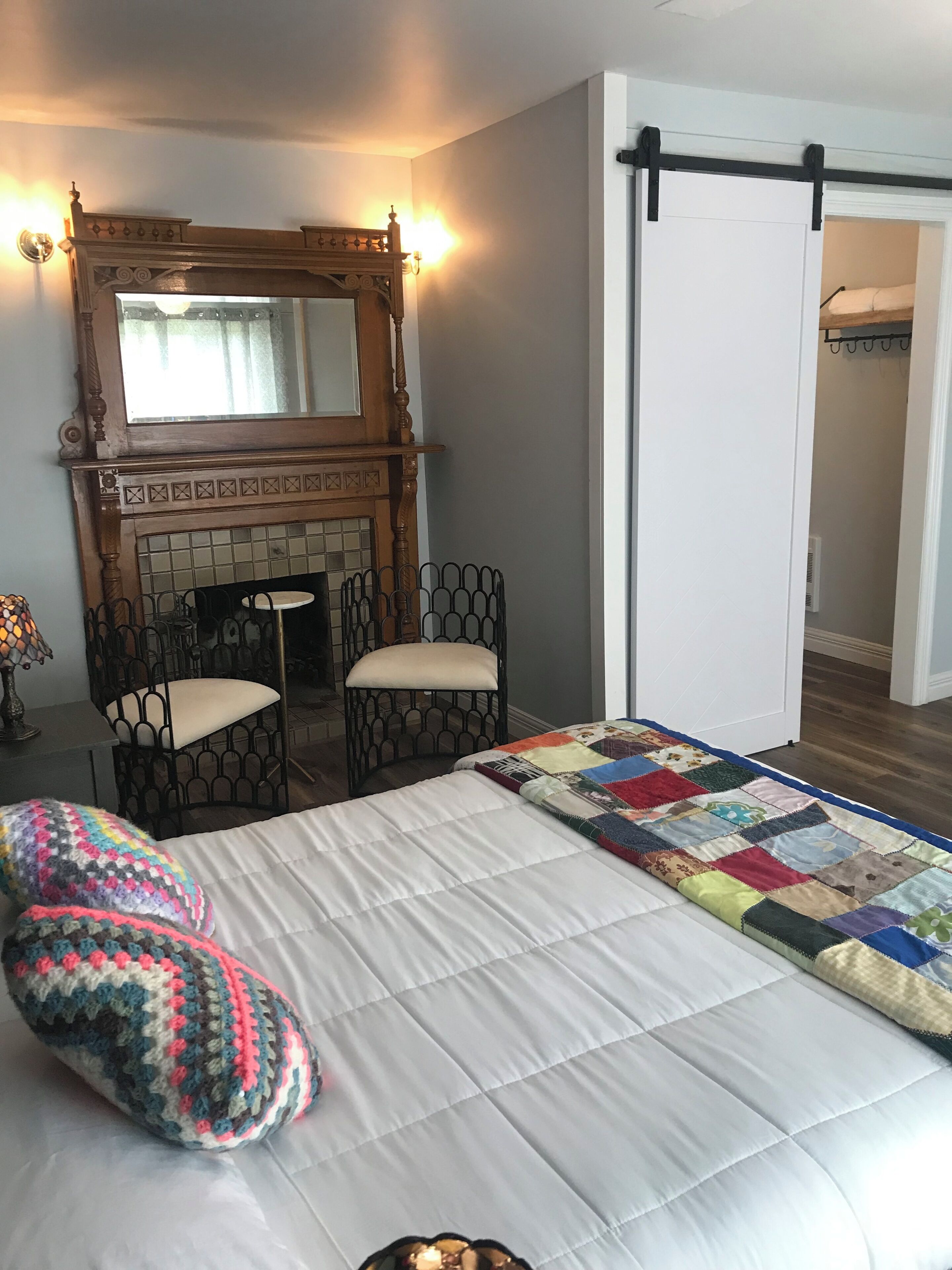 Une chambre à coucher avec un lit, deux chaises, une cheminée et une porte.