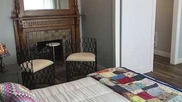 Une chambre à coucher avec un lit, deux chaises, une cheminée et une porte.