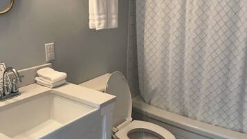 A bathroom with a white sink, toilet, and shower curtain.