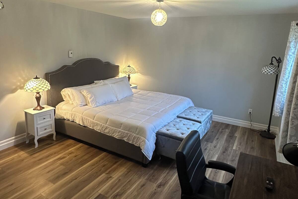 Un dormitorio con cama, mesitas de noche, un escritorio y una silla.