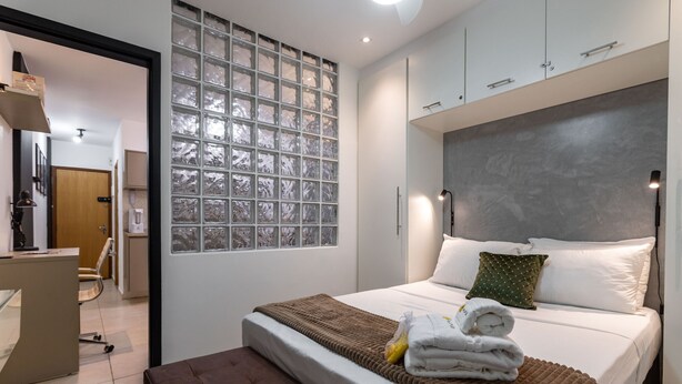 A modern hotel room with a large bed, a desk, and a view through a frosted glass window. - In front of the underground and 8 minutes from the beach | SF228 (Rio de Janeiro)