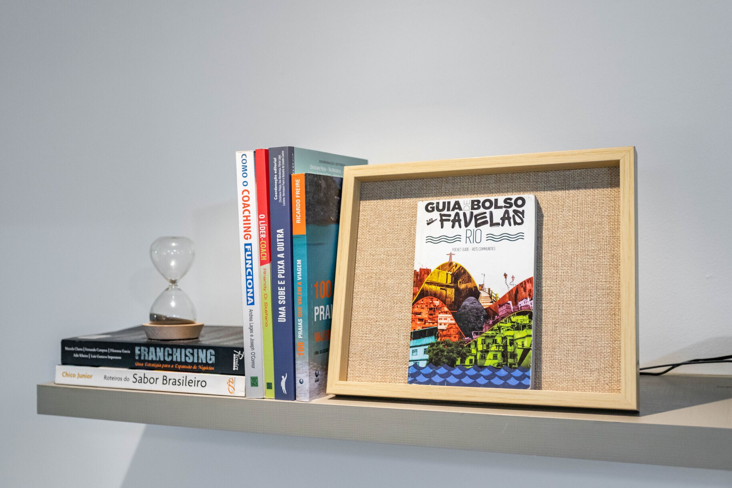 Una estantería con libros y un cuadro enmarcado de Río de Janeiro.