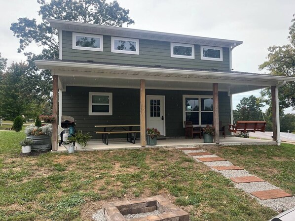A two-story house with a covered porch, a front door, and a small front yard with a pathway leading to the entrance.
