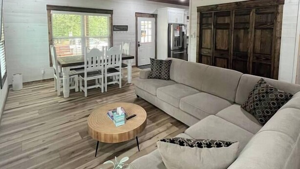Un vaste espace de vie doté d’un plafond en bois, d’un grand canapé, d’une table à manger avec des chaises et d’un ventilateur de plafond.