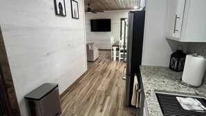 Une cuisine moderne avec un plancher en bois, des armoires blanches et un comptoir en granit.