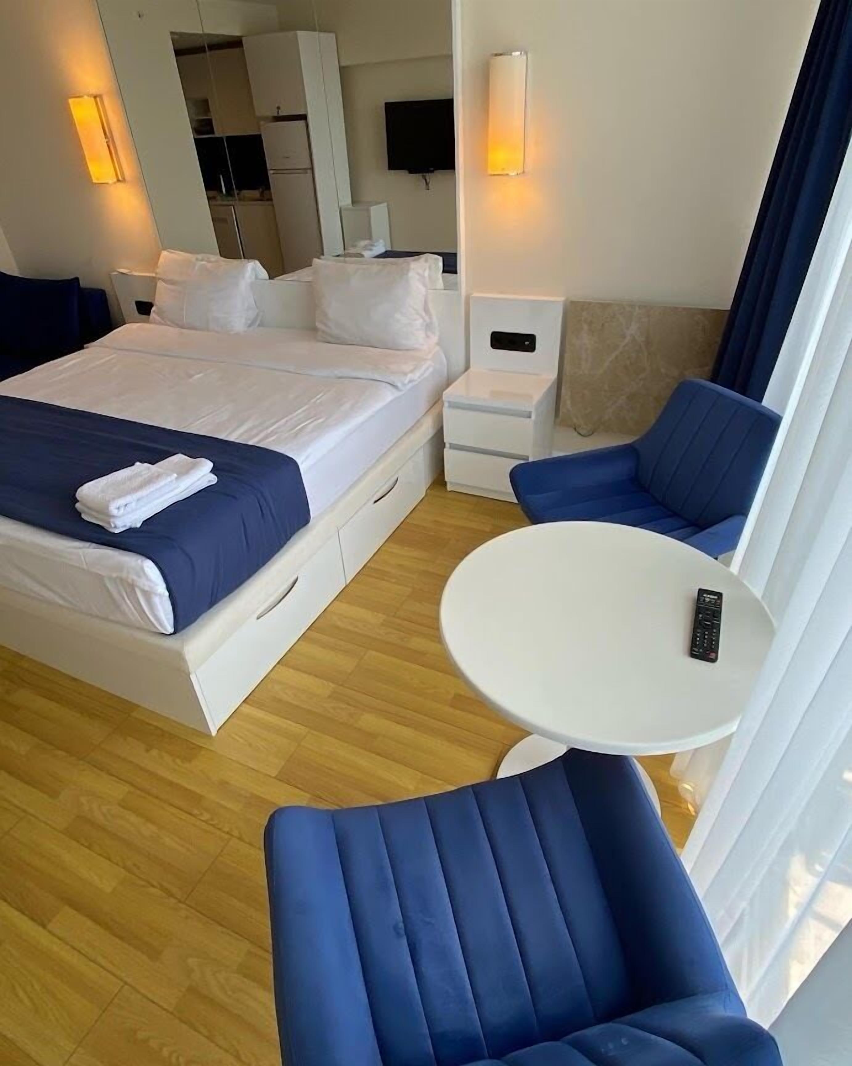 Een hotelkamer met een bed, nachtkastje, stoel, klein tafeltje en een televisie.