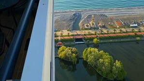 A balcony with a view of the sea and a beach area with construction equipment.