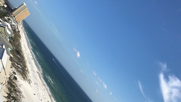 A beach with a clear sky, a sandy shore, and a few buildings in the background. - 3 bedroom condo on the 12th floor in beautiful Panama City Beach (Panama City Beach)