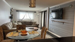 A modern living room with a sofa, a glass coffee table, and a TV mounted on the wall. - 3 bedroom condo on the 12th floor in beautiful Panama City Beach (Panama City Beach)