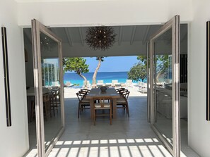 Une terrasse ouverte avec une table et des chaises, un luminaire suspendu et une vue sur l’océan.