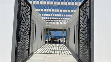 A covered outdoor area with a pergola, leading to a beach view.