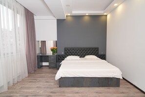 Relax in a spacious room with a large bed, desk, and vase with flowers.