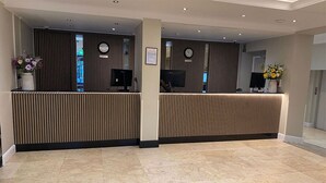 Een receptie met twee balies, een klok en een ingelijste mededeling aan de muur.