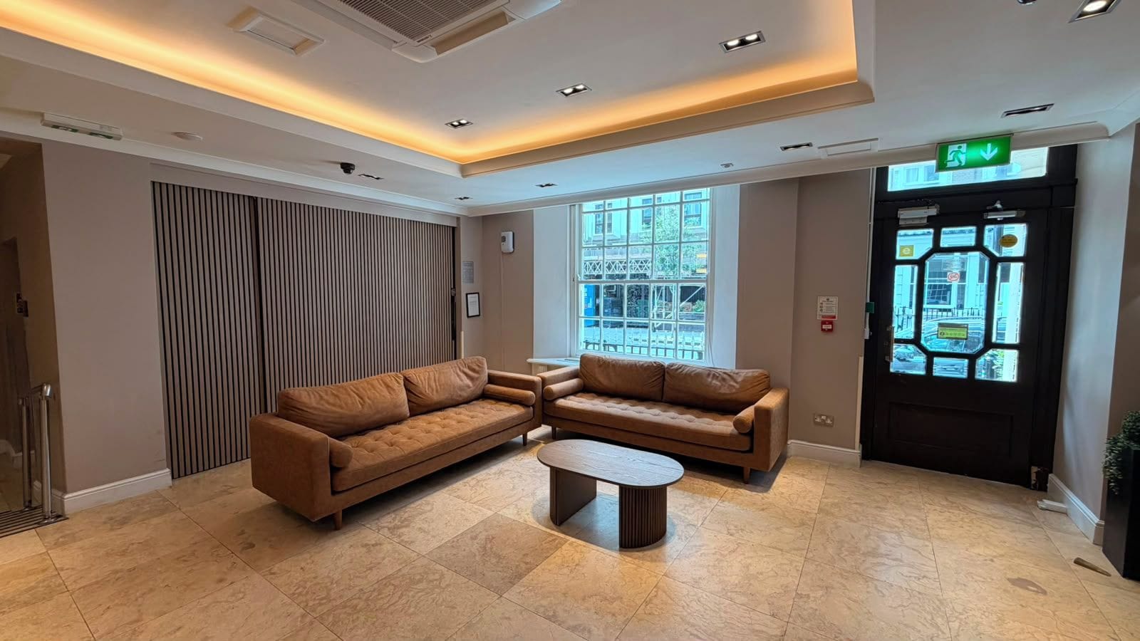 A modern lobby with a sectional sofa, a coffee table, and a large window providing a view of the outside.