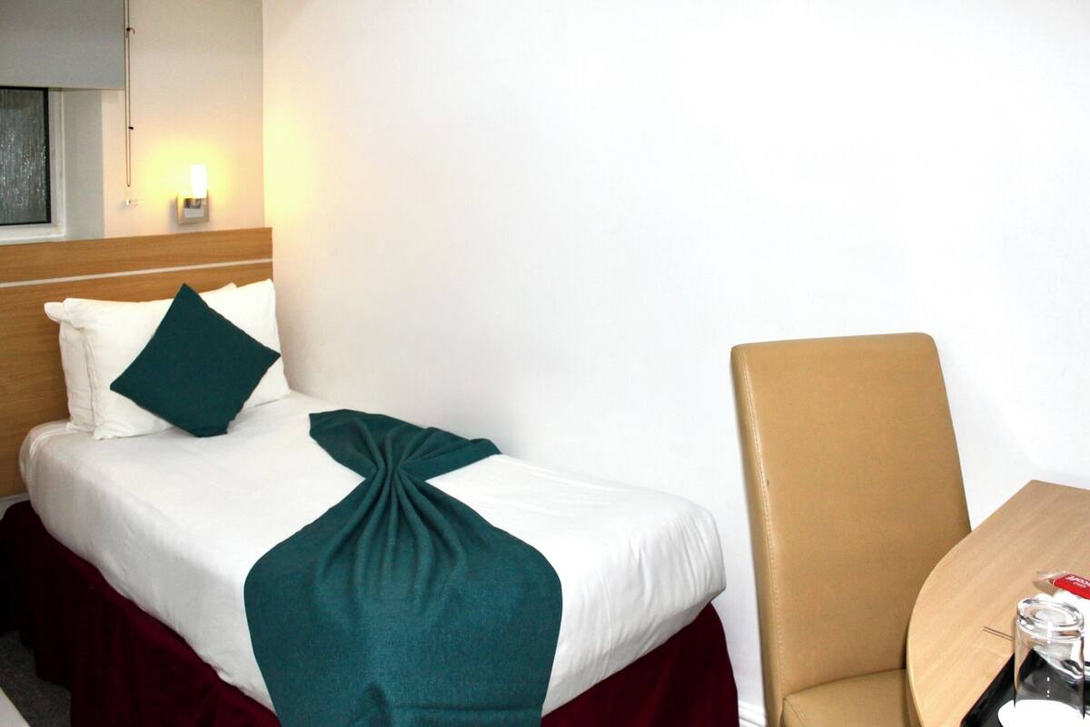 A hotel room with a bed, a chair, and a table.