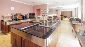 Een modern café met een centrale balie, een zithoek en zicht op de eetruimte.