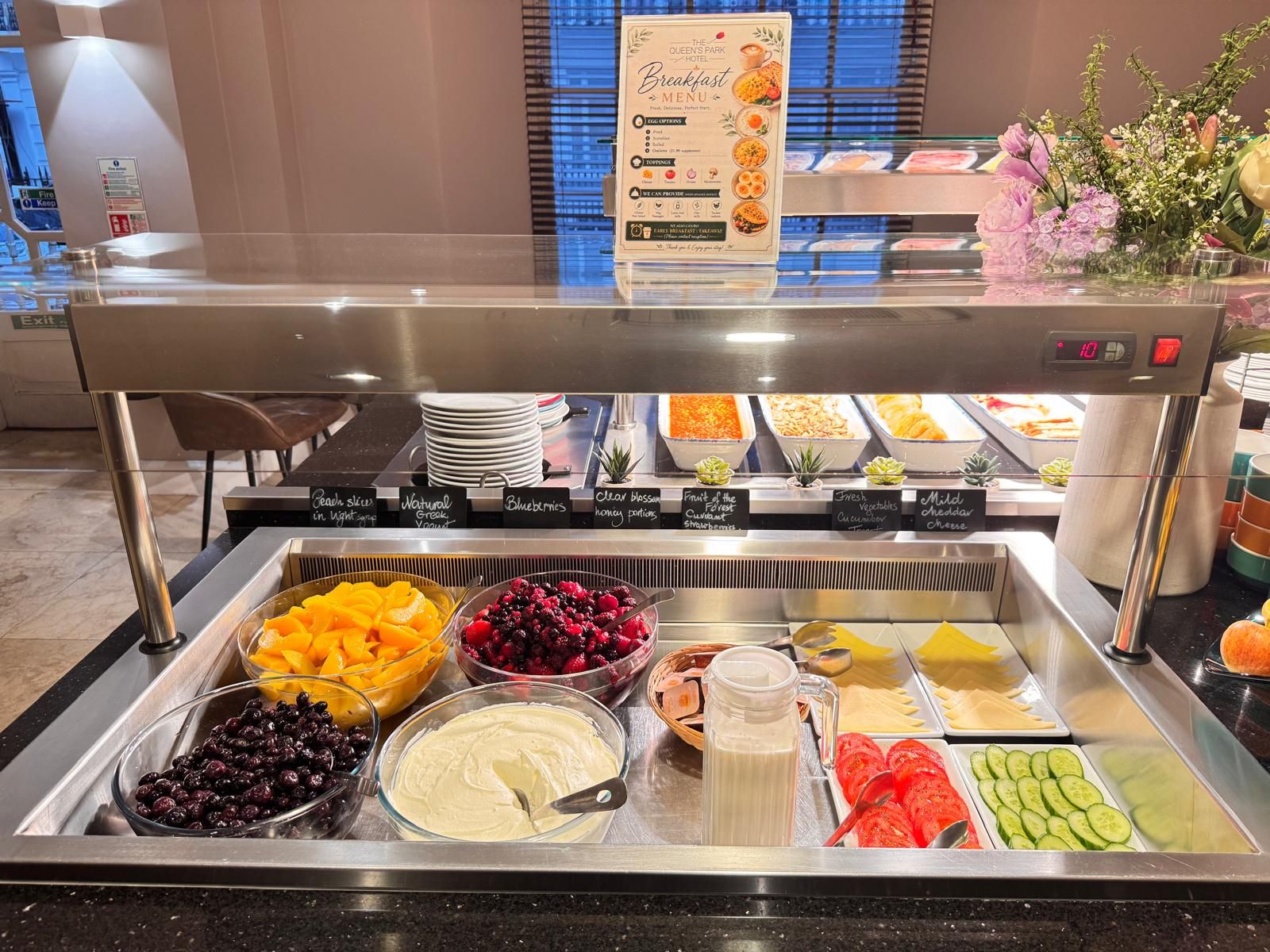 A buffet breakfast setup with various food options including fruits, yogurt, and cereal.