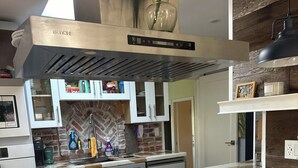 Una cucina moderna con isola centrale, elettrodomestici in acciaio inossidabile e una parete di fondo in mattoni.