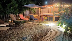 Un patio con pavimento in legno, circondato da una recinzione in legno, arredato con due poltrone e un tavolino.