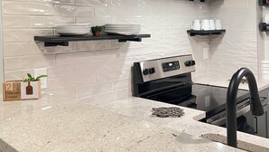 A kitchen with white subway tiles, black floating shelves, a stainless steel range hood, and a built-in oven. - Stunning Loft  from 1860 in Frechtown St Charles Mo (Saint Charles)