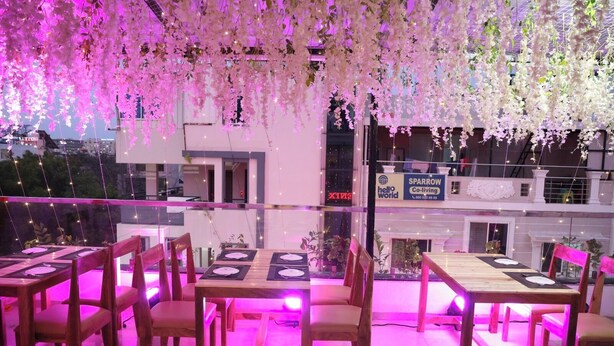 An outdoor dining area with tables and chairs, string lights, and hanging floral decorations. - Wishotel Premier The Phoenix Hotel 2.O (Indore)