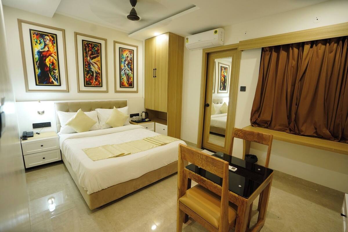 Habitación de hotel con cama, mesitas de noche, una silla, escritorio y un espejo grande.