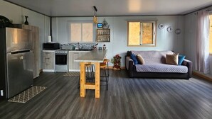 Een moderne keuken met een centraal eiland, een eetgedeelte met een houten tafel, en een gezellige zithoek met een bank.