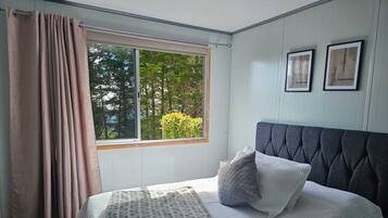 A bedroom with a bed, a window with curtains, and framed pictures on the wall.