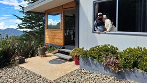 Uma casa moderna com porta de madeira, uma janela grande e um caminho de pedra que leva à entrada.