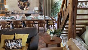 Una sala de estar acogedora con un sofá y un sillón, un comedor con una mesa dispuesta para una comida, y un cuadro grande en la pared.