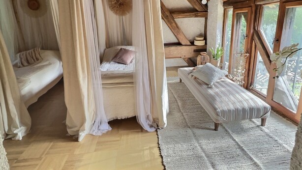Un dormitorio acogedor con una cama a dosel, un banco y vistas al exterior.