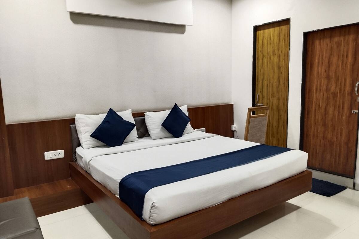 Une chambre d’hôtel moderne avec un grand lit, une tête de lit en bois et une porte en bois.