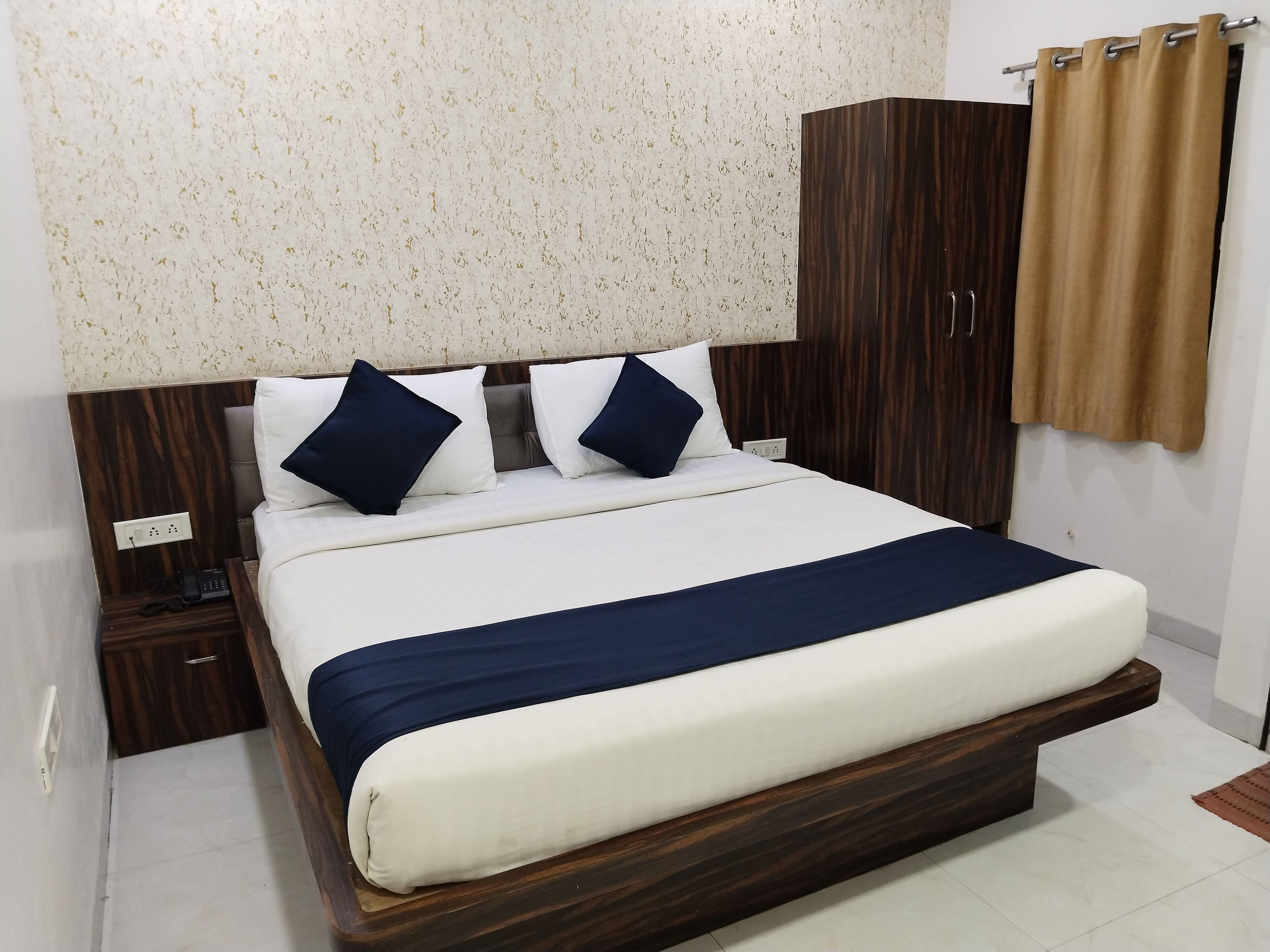 A neatly made bed with a wooden headboard, a bedside table, and a wardrobe.