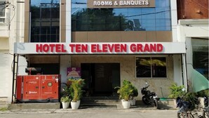 Un hôtel appelé « Hotel Ten Eleven Grand », avec une grande enseigne sur la façade indiquant « 10-11 Grand » et « Chambres et salles de réception ».
