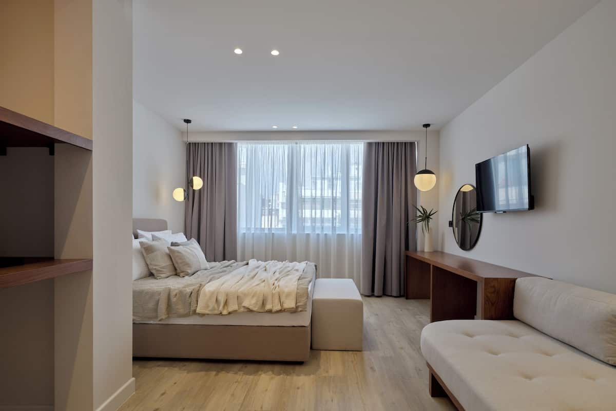 A modern bedroom with a bed, a sofa, a TV, and a desk.