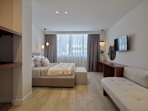 A modern bedroom with a bed, a sofa, a TV, and a desk. - Haya Athens Loftie Suites (Athens)