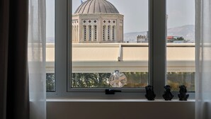 Vista attraverso una finestra con cornice decorativa, una ventola a soffitto e due piccole statuine sul davanzale.
