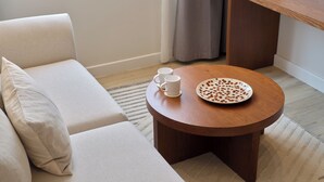 Un accogliente soggiorno con un tavolino rotondo in legno, due tazze bianche e un piatto decorativo.