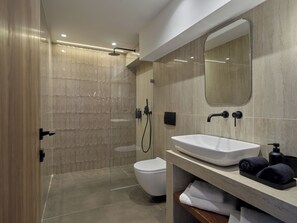 A modern bathroom with a glass-enclosed shower, a white toilet, and a vanity with a sink and towel rack. - Haya Athens Loftie Suites (Athens)
