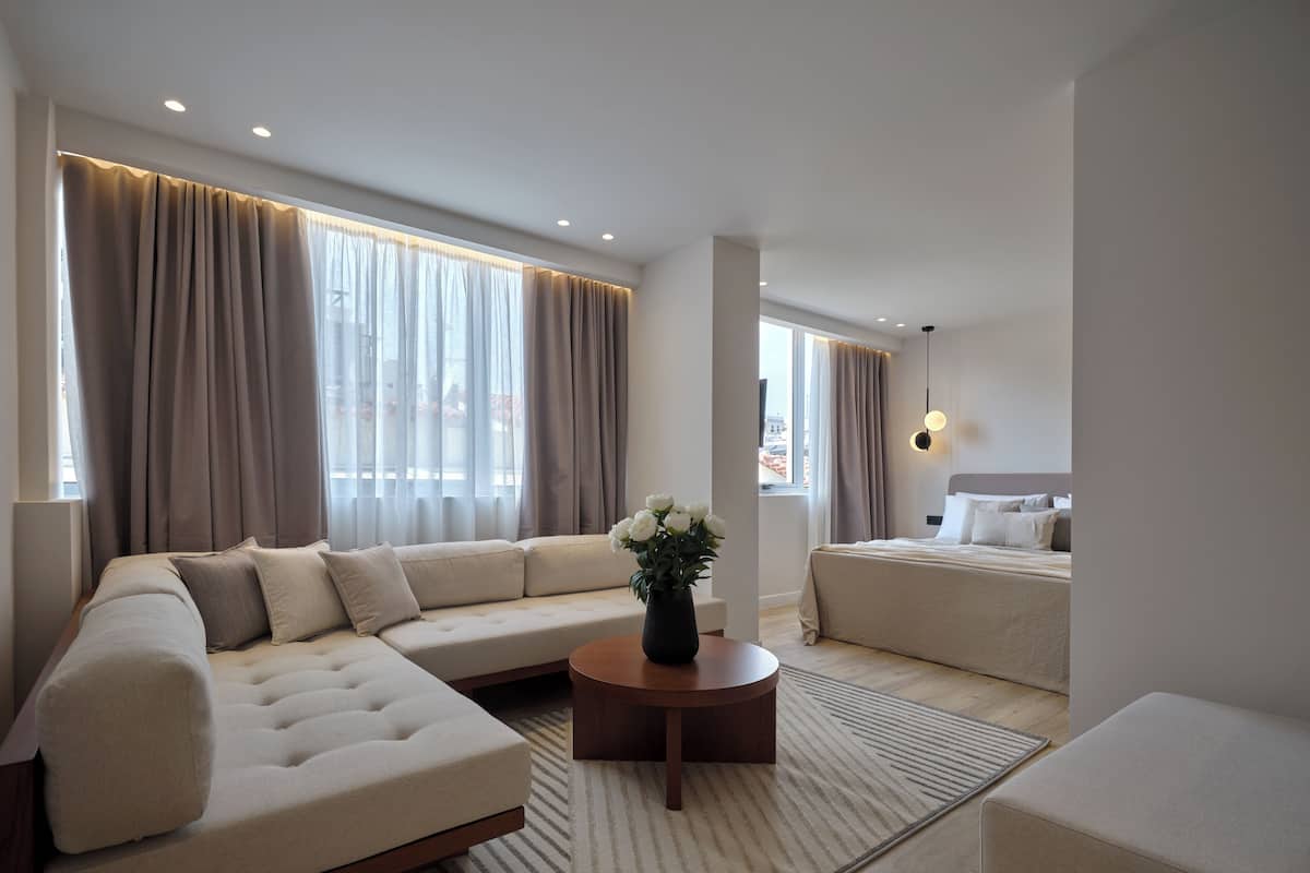A modern living room with a sectional sofa, a round coffee table, and a bed with a headboard.