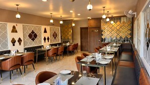 A restaurant with multiple dining tables and booths, equipped with modern lighting fixtures and decorative wall panels. - Wishotel Inn Skymoon  (Indore)