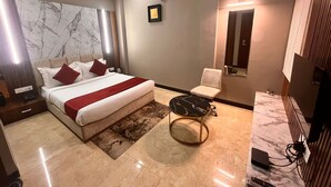 A modern hotel room with a large bed, a small round table, a chair, and a ceiling fan. - Wishotel Inn Skymoon  (Indore)