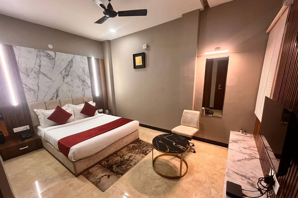 Ein modernes Hotelzimmer mit einem großen Bett, einem kleinen runden Tisch, einem Sessel und einem Deckenventilator.